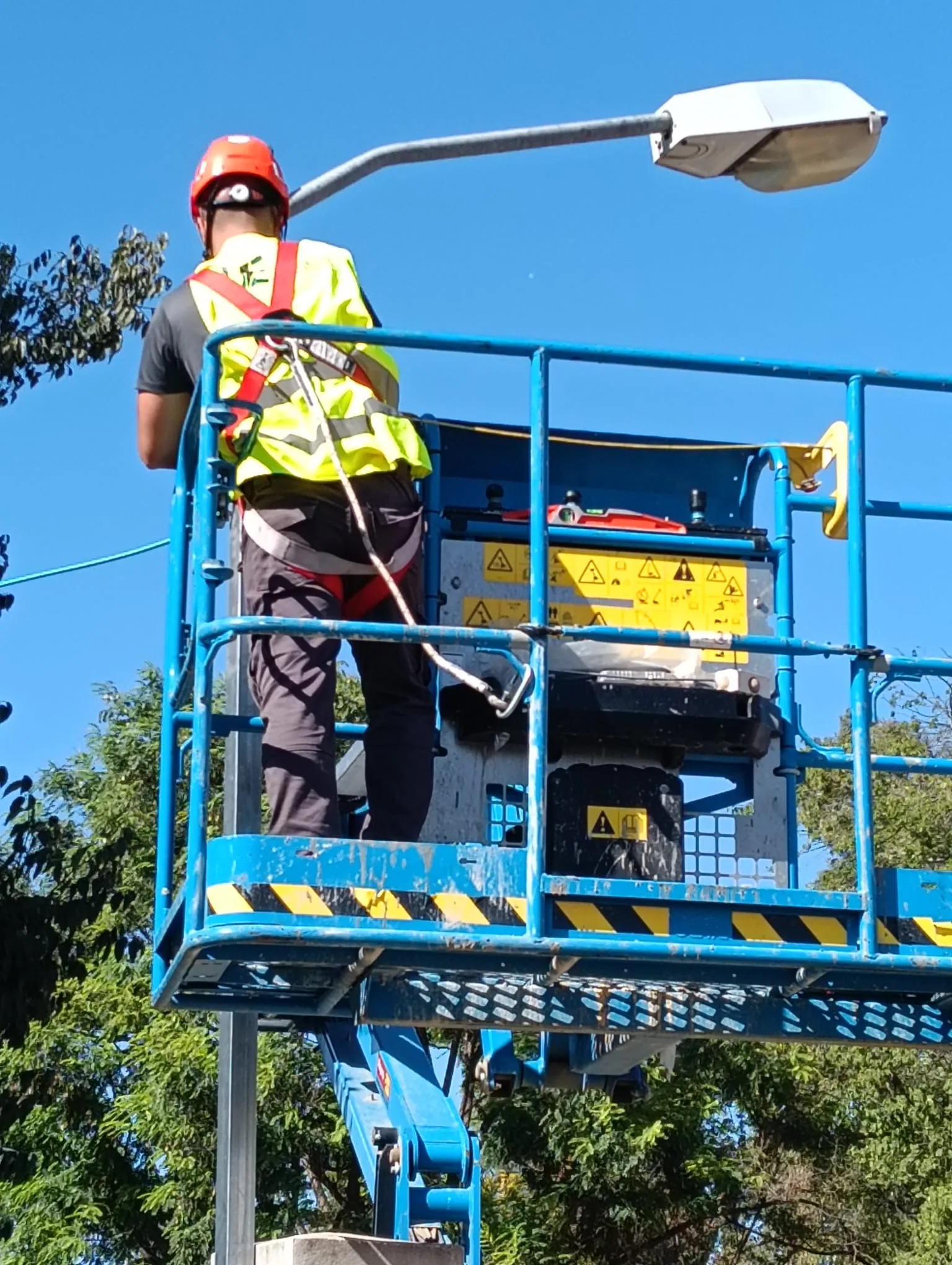 Técnico eléctrico en plataforma elevadora realizando instalación de farola de alumbrado público en Valencia