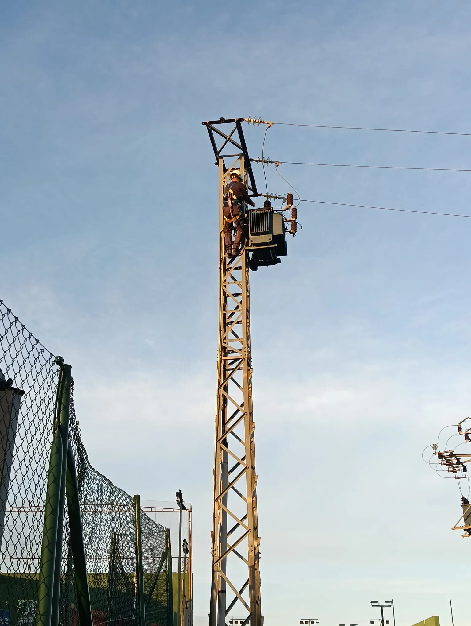 Técnico instalando transformador en apoyo de línea de alta tensión al atardecer en Valencia
