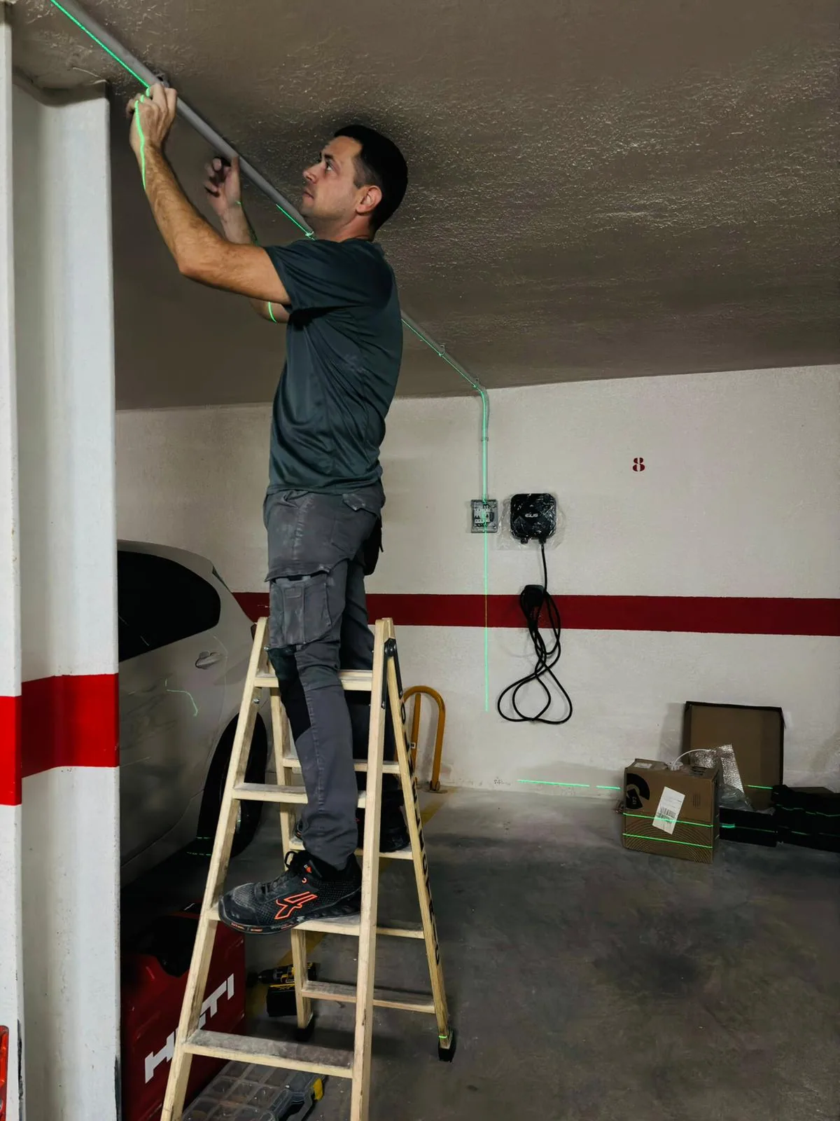 Técnico instalando canaleta y punto de recarga wallbox en garaje comunitario para vehículo eléctrico