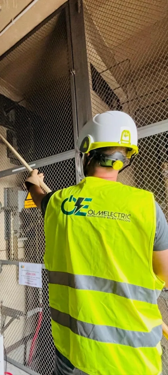 Técnico de OLMELECTRIC con chaleco y casco inspeccionando el interior de un centro de transformación