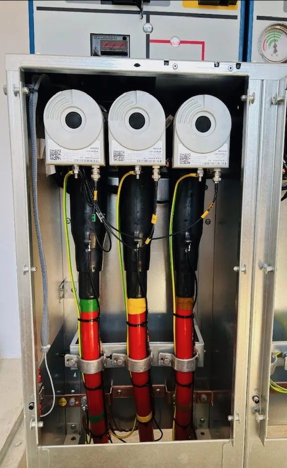 Terminales enchufables de cables de media tensión con capuchas rojas en celda MT de alta tensión